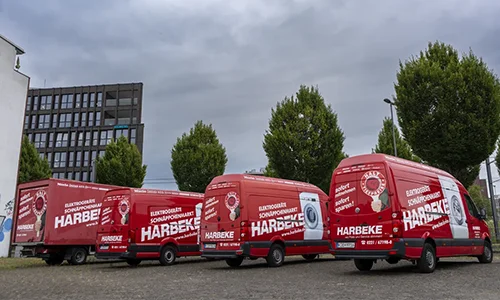 harbeke-service-web-02 Harbeke • Rote Lieferwagen von Harbeke auf Parkplatz unter bewölkten Himmel.