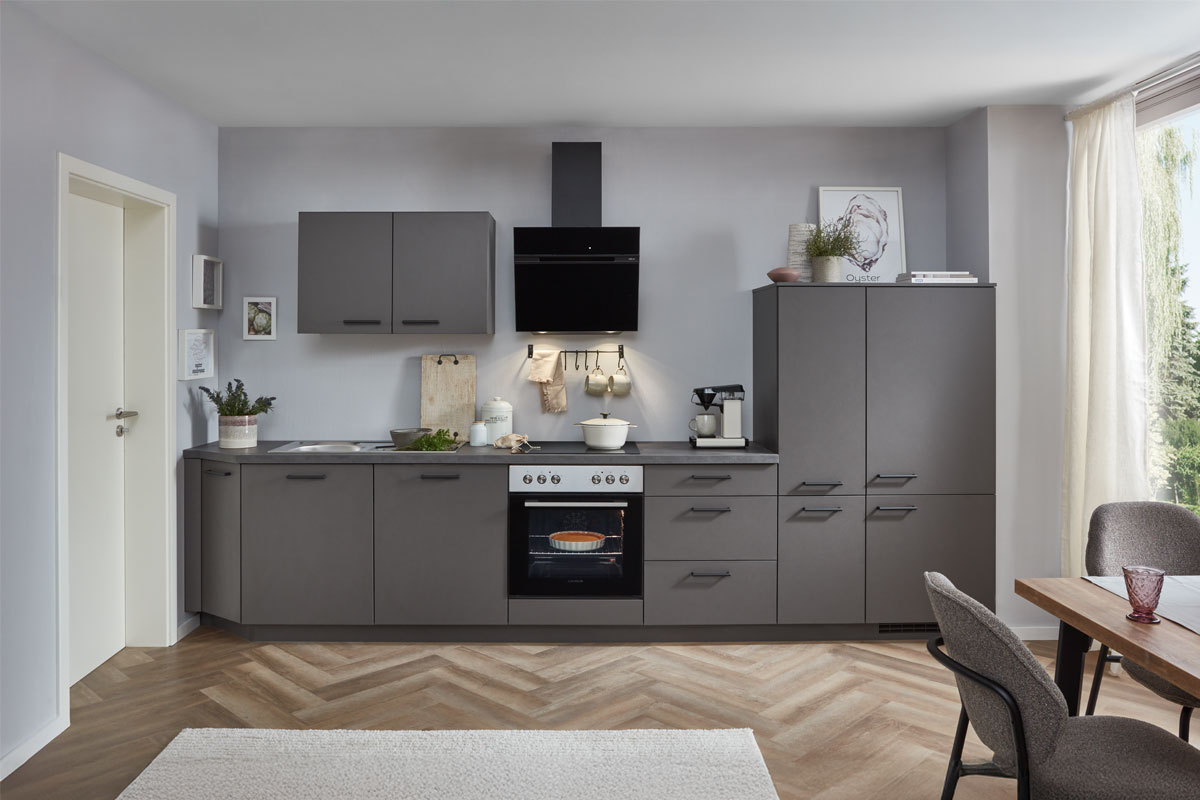 Harbeke • Moderne graue Küche mit Herd, Kühlschrank und Esstisch.