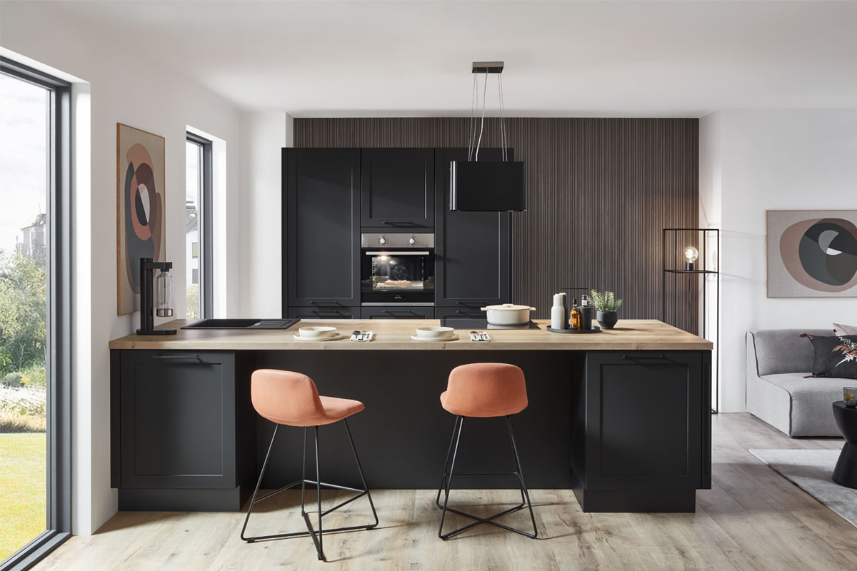 Harbeke • Moderne schwarze Küche mit Holztisch und stilvollen Barhockern.